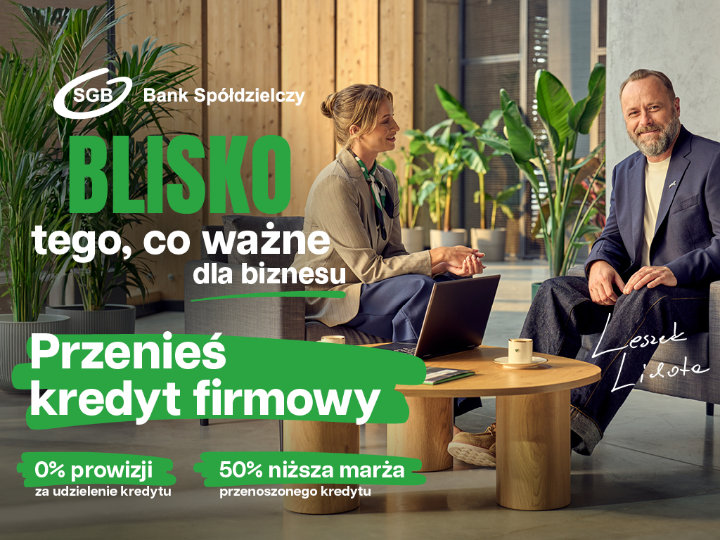 Dwie osoby w strojach biznesowych rozmawiają w nowoczesnym biurze. Tekst promocyjny w języku polskim reklamuje przeniesienie kredytu biznesowego z obniżoną prowizją i niższymi marżami.